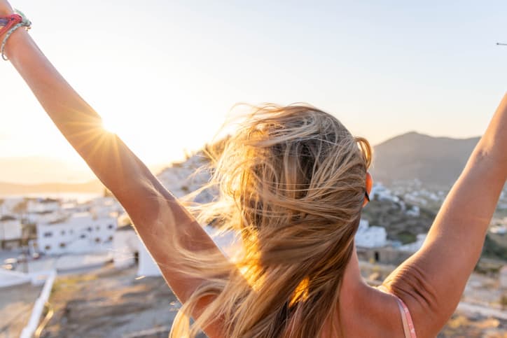 Persona vista di spalle che alza le braccia verso il cielo