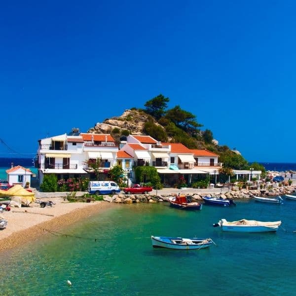 A daytime view of Kokkari Beach, Samos. The green and turquoise blue sea and the settlements along the shore.