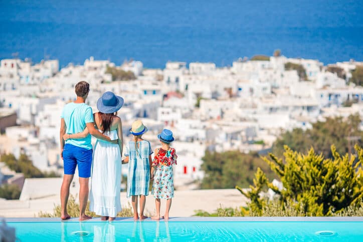 Une famille avec un père, une mère et deux petites filles devant le panorama d'une ville grecque.