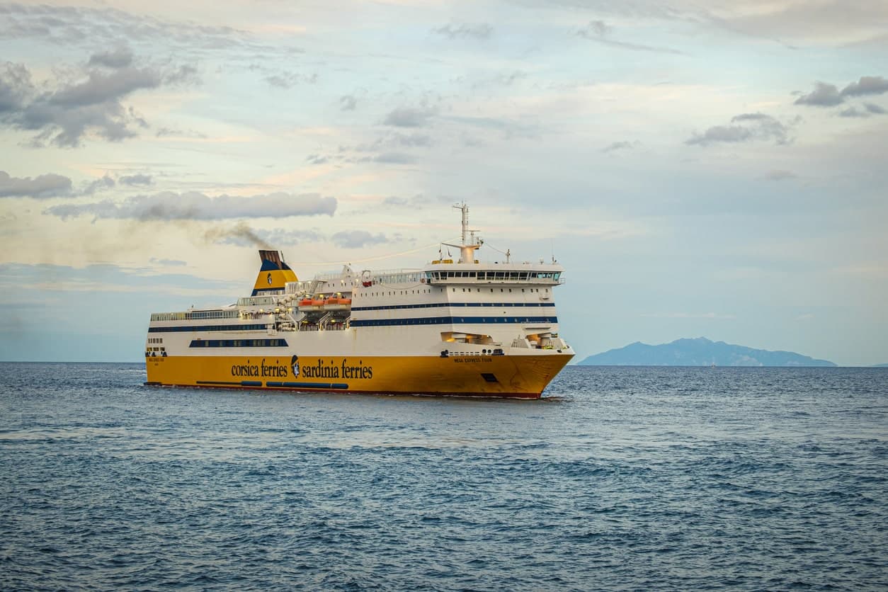 Ferry jaune et blanc de Corsica Ferries en mer avec une île en arrière-plan.