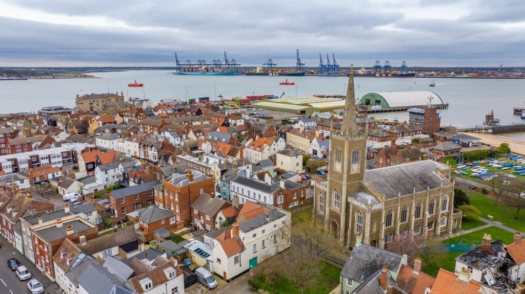 Luftaufnahme von Harwich, England, mit einer Kirche, roten Ziegeldächern und dem Hafen im Hintergrund.