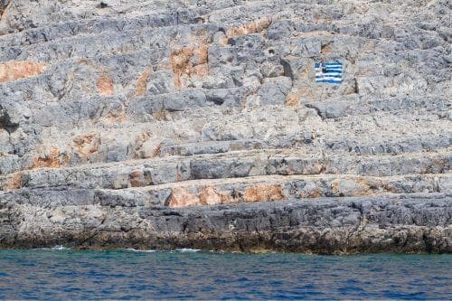 sten i Pserimos med den grekiska flaggan