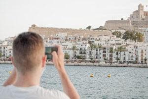 man holding up his phone and taking a photo of ibiza