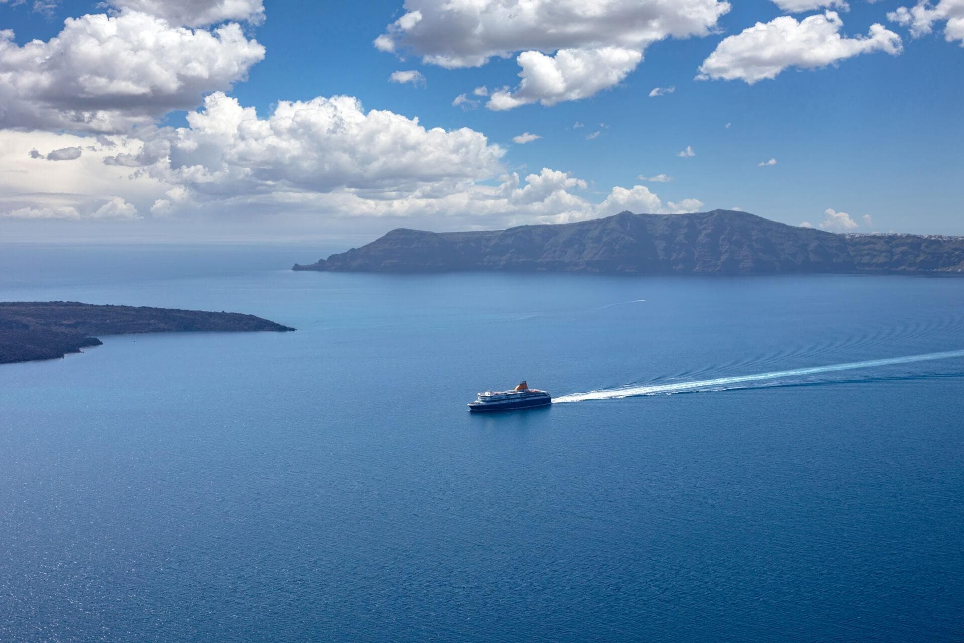 ferry sailing along the blue seas with crowds in the background