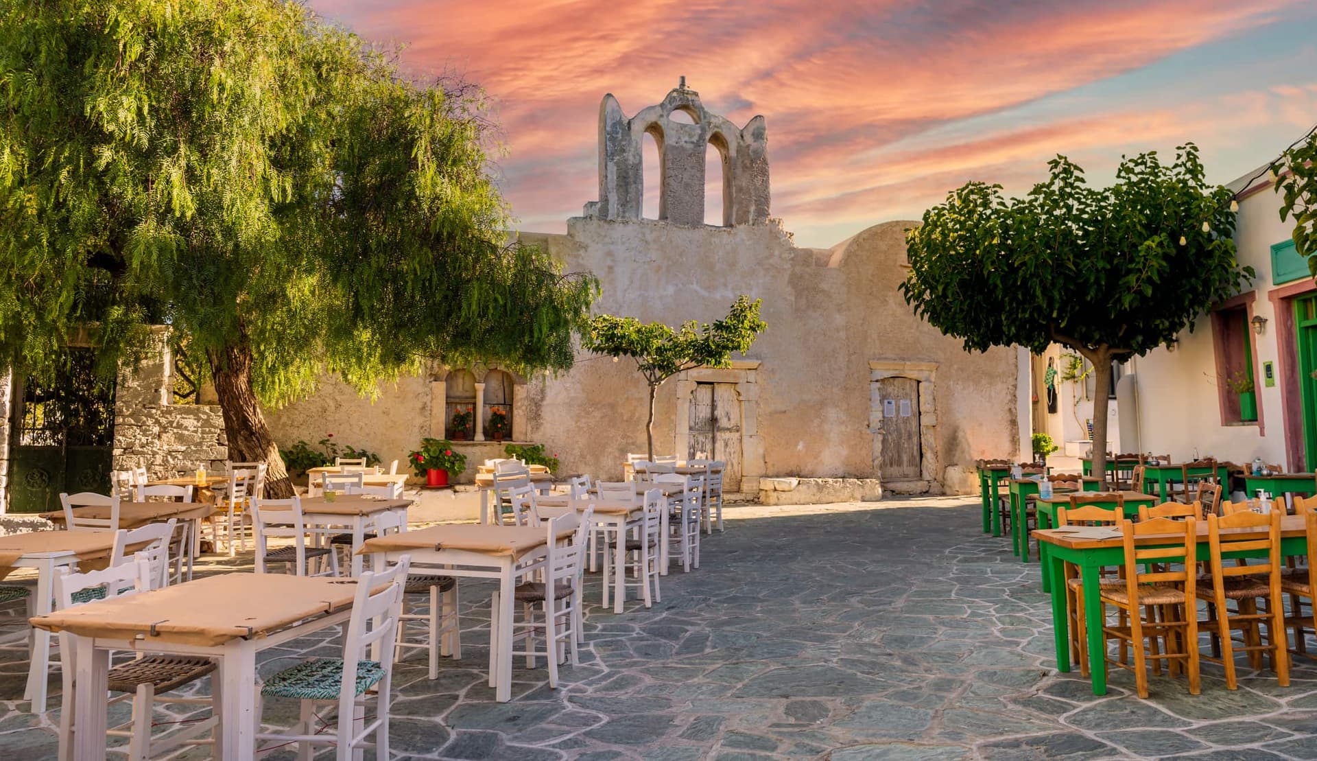 A quiet, cobblestone alley in Folegandros, where traditional tables, whitewashed buildings, and the warm light of dusk come together to create the island’s authentic atmosphere.