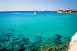 mujer en traje de baño rojo nadando en el agua turquesa de karpathos