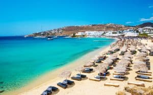 playa de mykonos con agua turquesa y sillas de playa