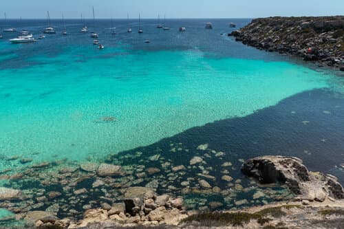 he famous Cala Azzurra beach on the beautiful island of Favignana, Sicily, during a sunny summer day.