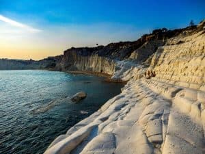Une plage à la falaise blanche spectaculaire sous un soleil couchant.