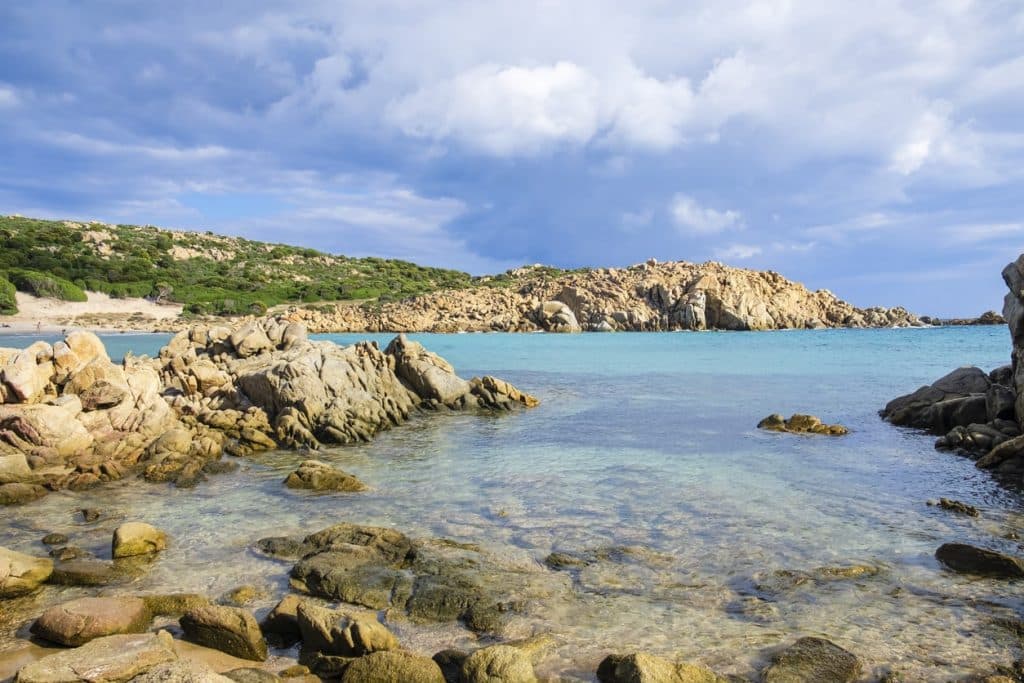 Granitfelsen, mediterrane Macchia und goldener Sand an der wunderschönen Cala Cipolla entlang der Küste von Chia.