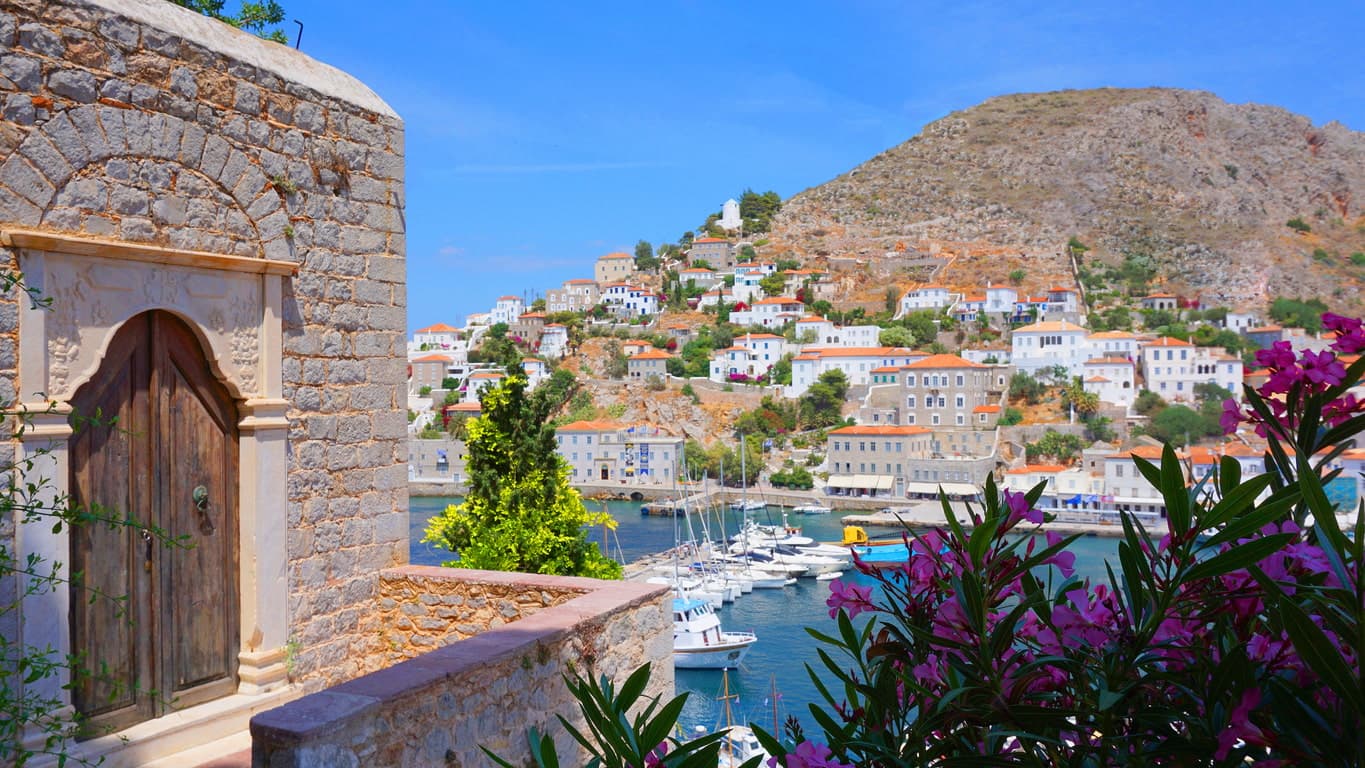 The enchanting Hydra with its stone-built mansions, the picturesque harbor and the island landscape unfolding between flowers and the sea.