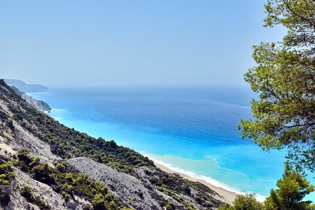Atemberaubender Blick auf eine griechische Küste mit türkisblauem Wasser, steilen Klippen und üppiger Vegetation.