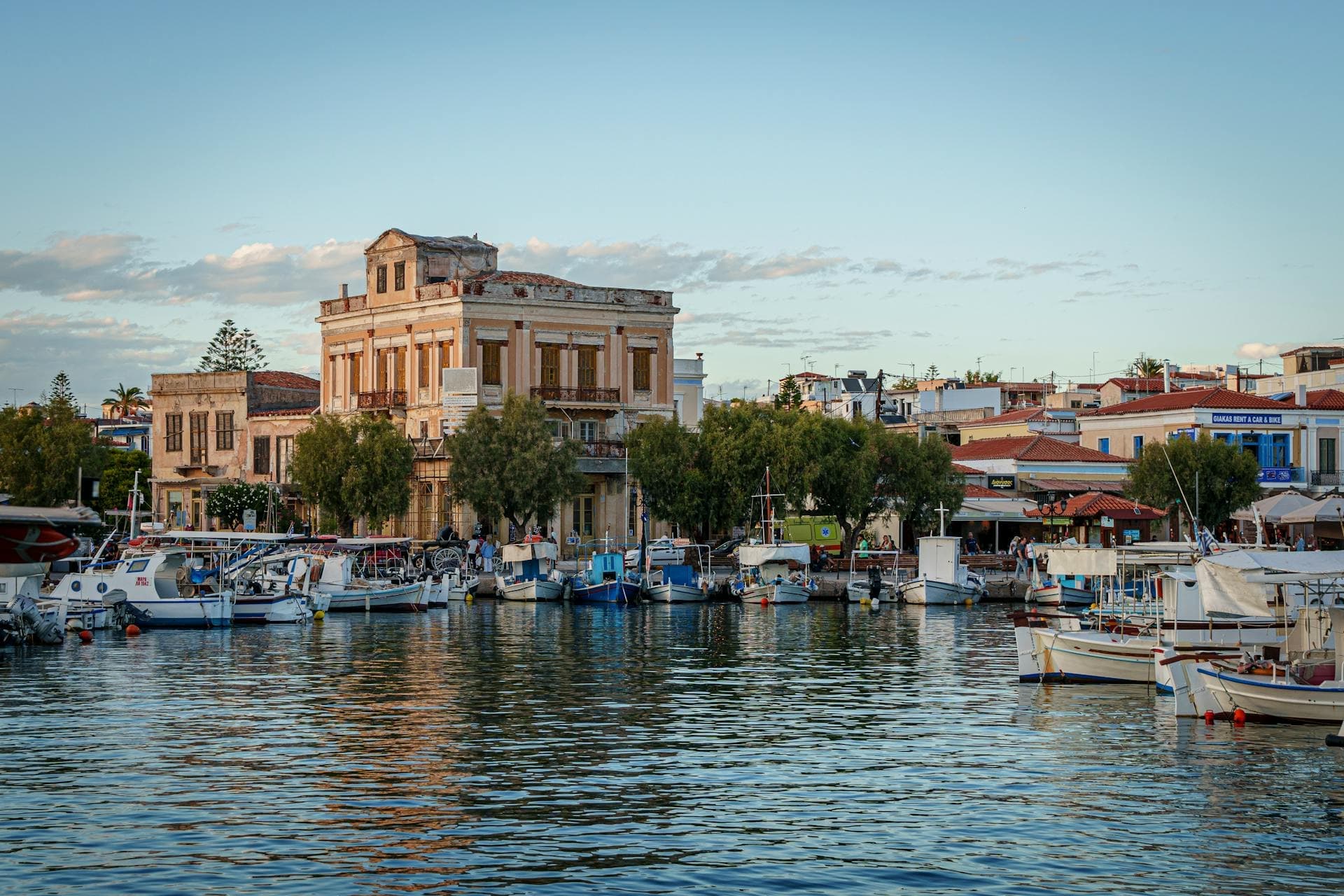 A marina on the Greek Island Aegina foregrounds a neoclassical building.