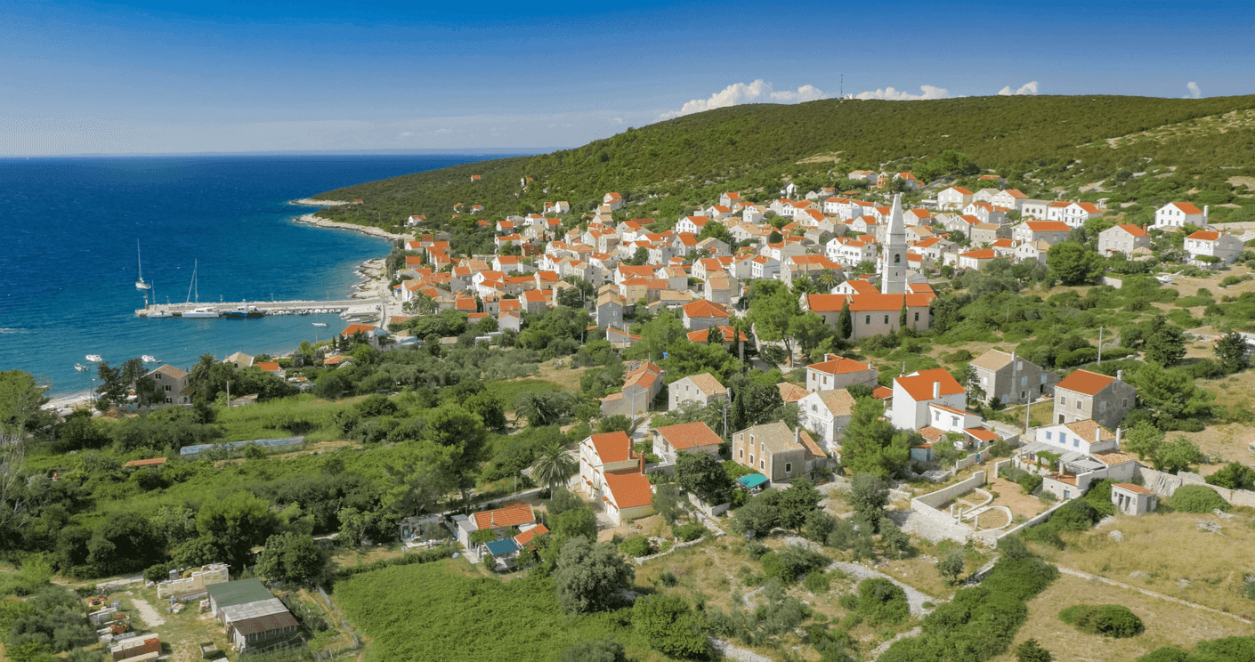 Pogled na crkvu i kućice na otoku Unije uz obalu okružene zelenilom