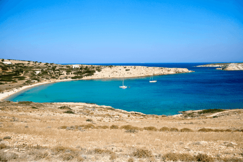 plage de sable avec des eaux bleues et quelques canots pneumatiques flottant sur l'eau