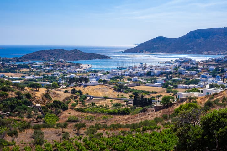 Veduta panoramica di Lipsi con case bianche, colline verdi e mare azzurro sullo sfondo.