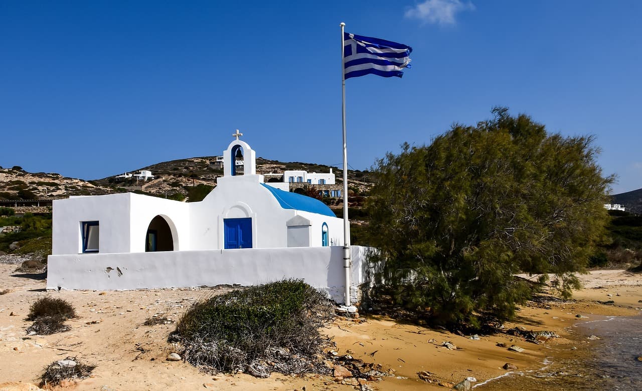 Une église traditionnelle grecque, le drapeau au vent, sur la plage.