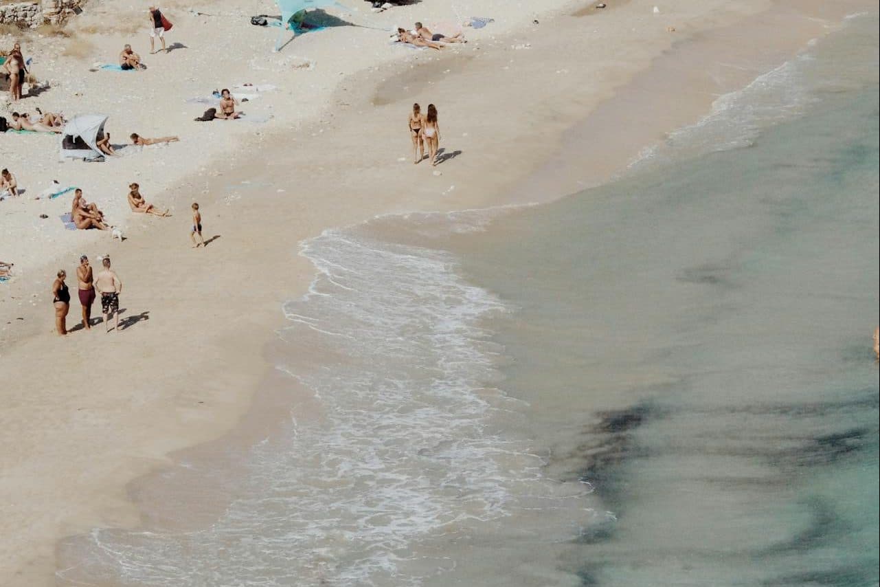 Une plage de sable blanc et une eau transparente, et quelques touristes