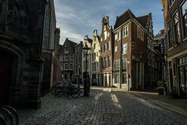 A charming, narrow cobblestone street lined with historic, gabled buildings typical of traditional Dutch architecture. 