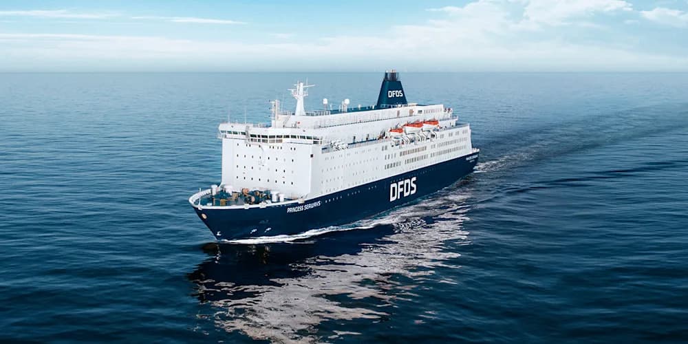 Ferry DFDS naviguant en pleine mer sous un ciel bleu limpide. Le navire, arborant le logo DFDS, offre un voyage pittoresque et relaxant sur l'eau.