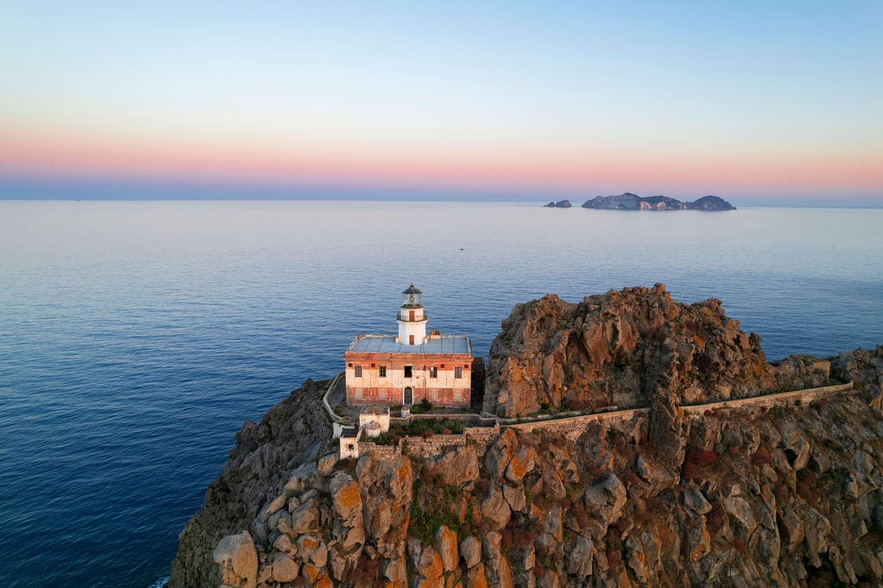 Faro storico arroccato su una scogliera a picco sul mare al tramonto
