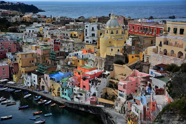 Pittoresco borgo costiero con case colorate disposte a terrazze lungo il pendio di Procida, una delle isole italiane economiche