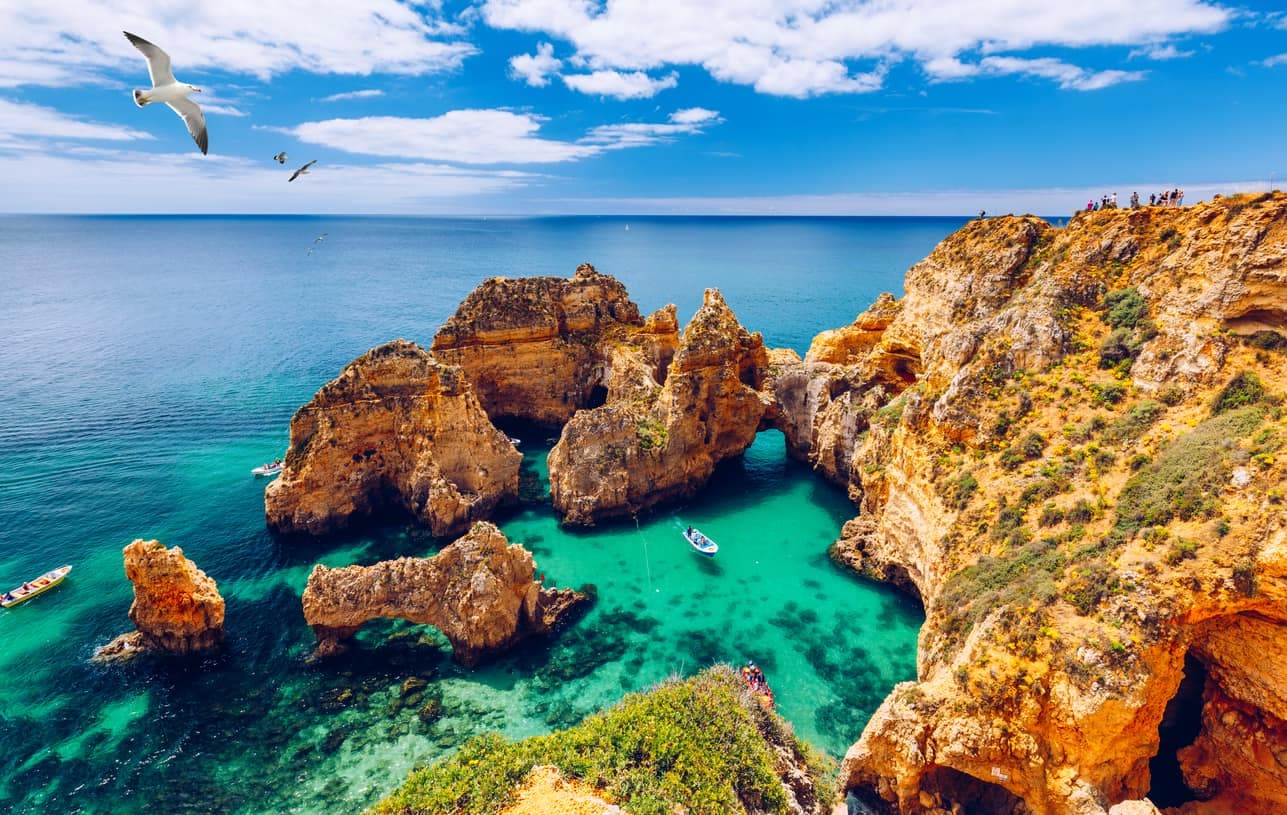 Steilküste mit Felsbögen und türkisfarbenem Wasser bei Lagos an der Algarve, Portugal.