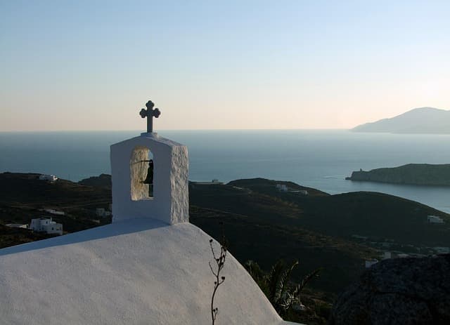 Tipico tetto a cupola bianca con campanile e croce, simbolo dell’architettura cicladica, sull’isola di Ios