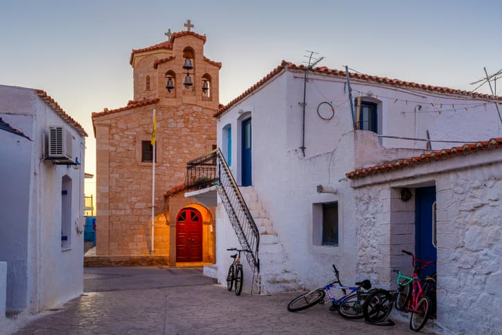 Λευκά παραδοσιακά σπίτια και καμπαναριό στο Αγκίστρι, φωτισμένα από το απαλό φως του φθινοπωρινού δειλινού.