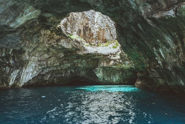 Intérieur d'une grotte marine avec des parois rocheuses et une eau d'un bleu turquoise éclatant à Marettimo.
