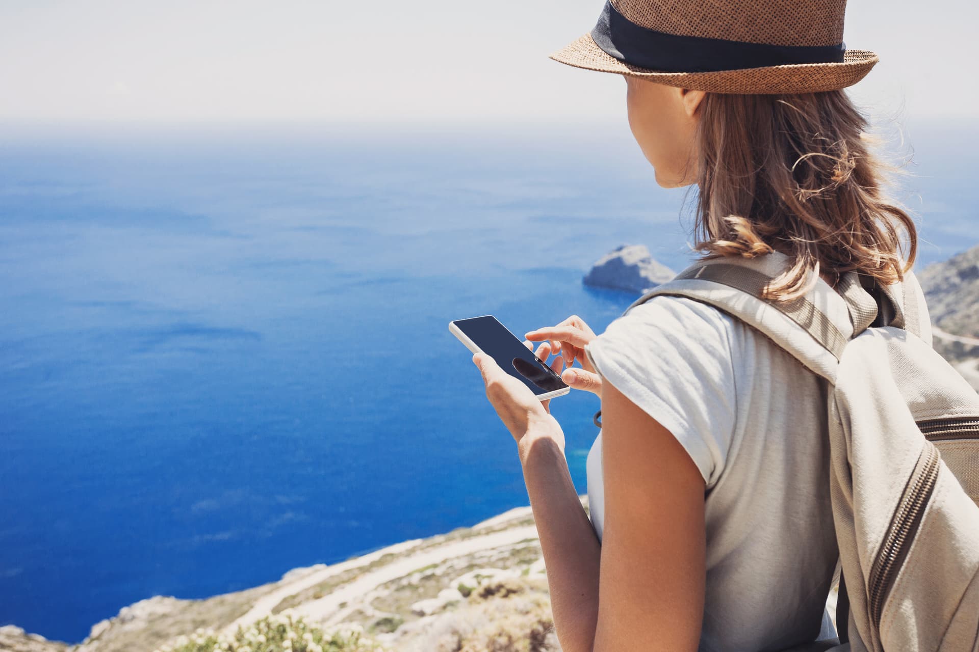 Une voyageuse solitaire explore les îles grecques, son téléphone portable à la main