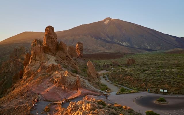Paesaggio del Parco Nazionale del Teide a Tenerife, con le formazioni rocciose di Roques de García e il vulcano Teide sullo sfondo al tramonto.