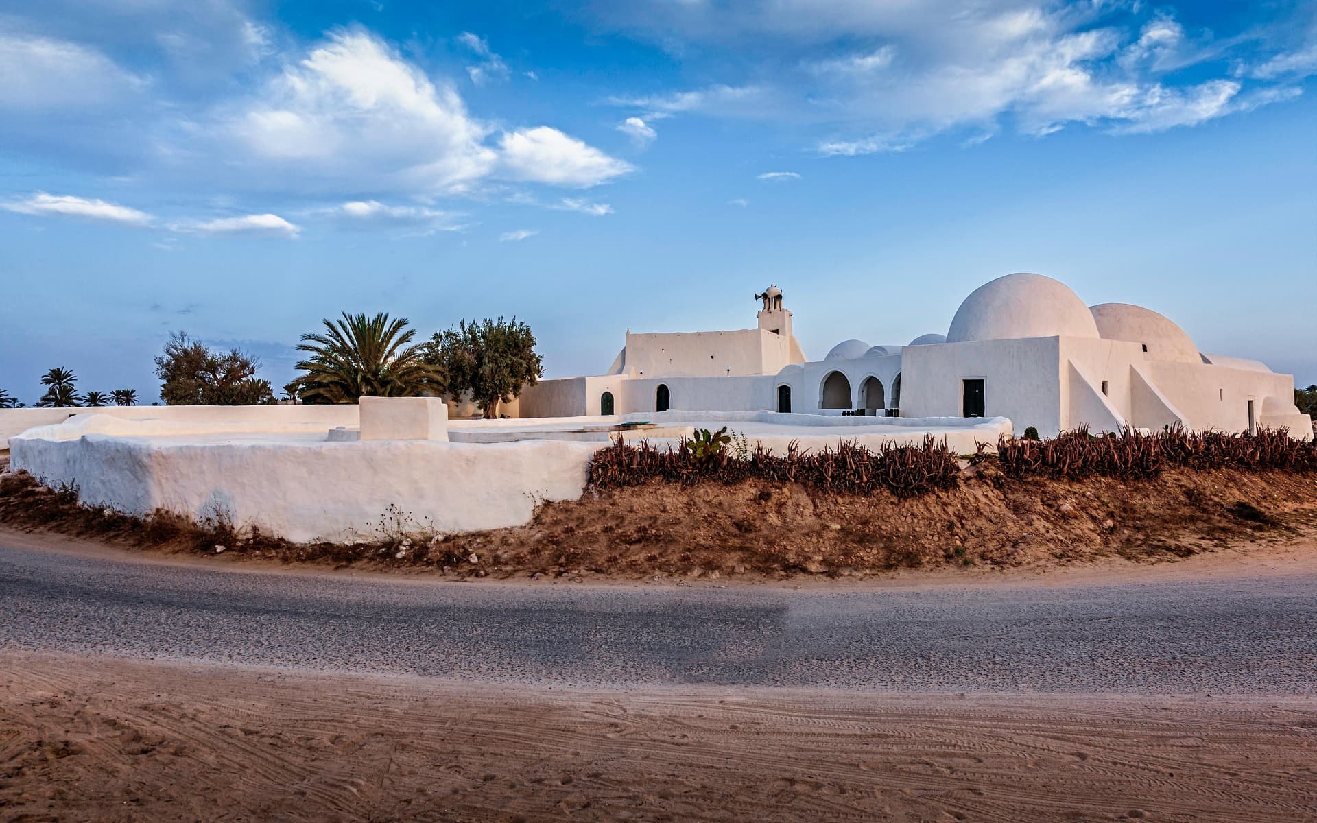 Une mosquée d'un blanc éclatant au bord de la plage sous un coucher de soleil.