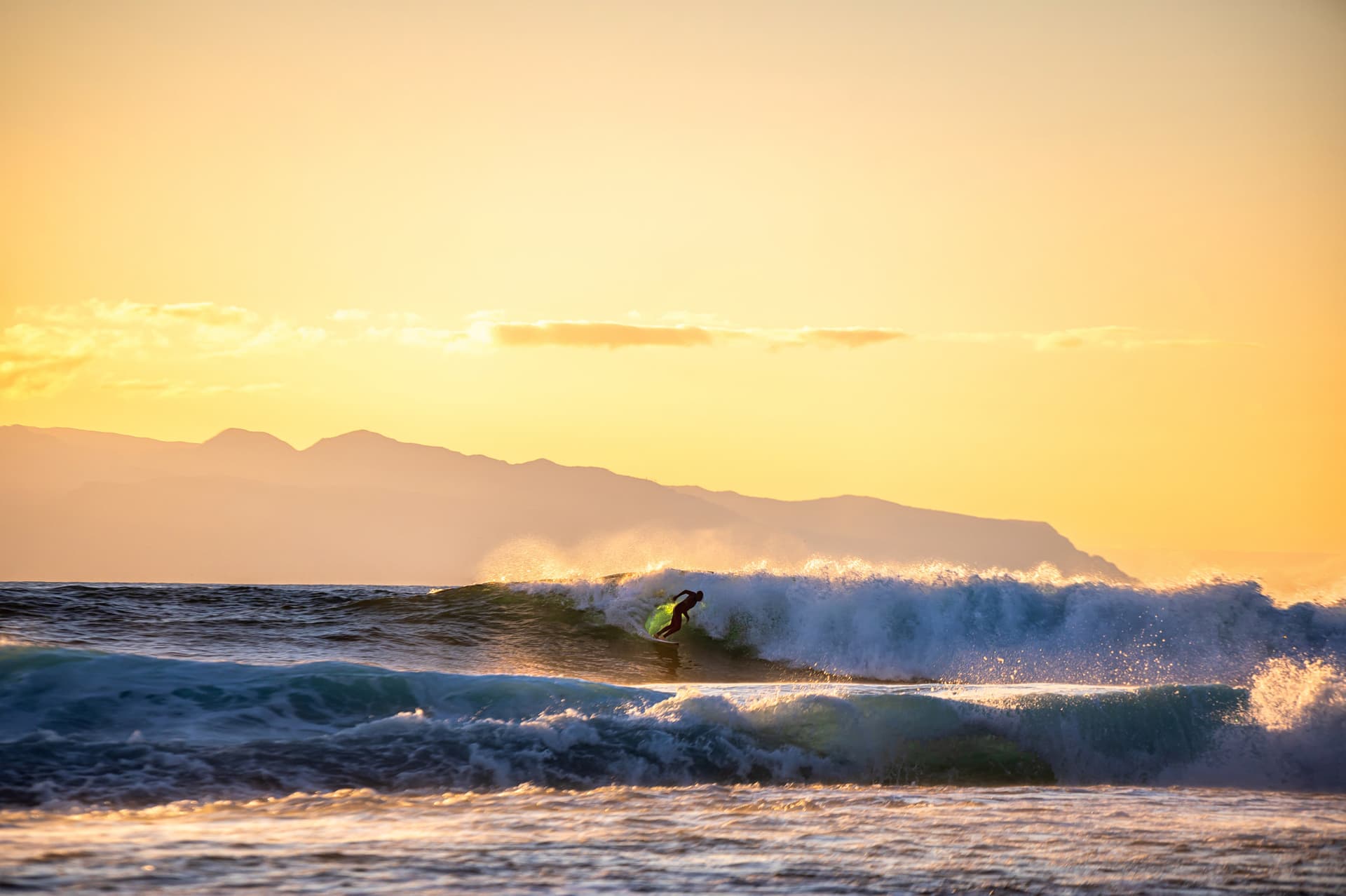 A surfer braving the waves on the coasts of Tenerife with La Gomera in the background