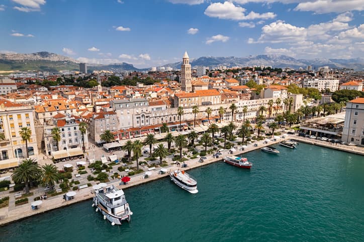 Vista sul porto di Spalato, in Croazia, con il lungomare Riva fiancheggiato da palme e gli edifici storici del centro sullo sfondo.