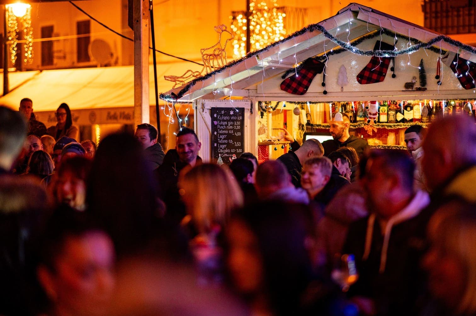 Bijela adventska kućica i brojni ljudi na adventu na otoku Lošinju.