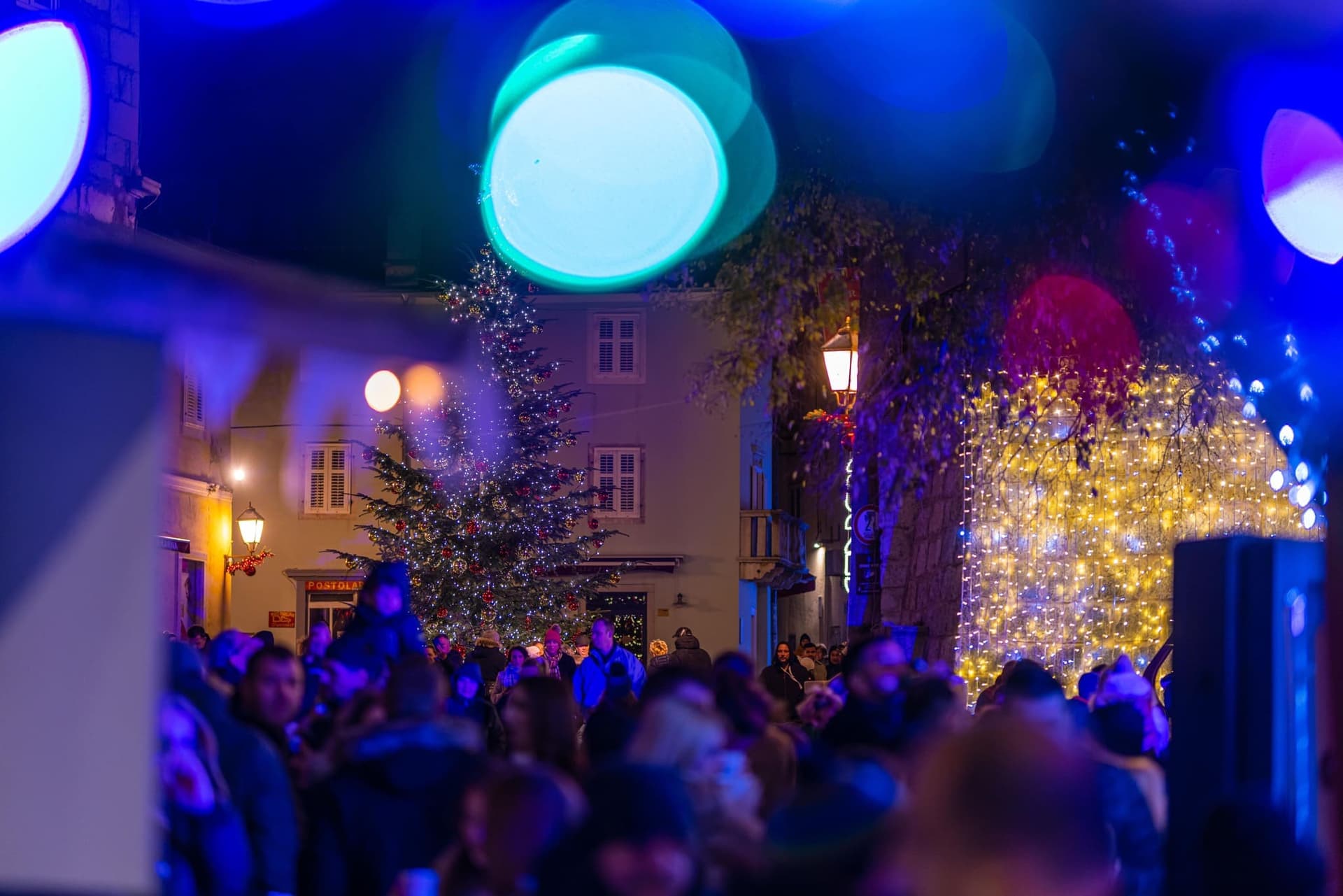 Okićena božićna jelka okružena brojnim ljudima na adventu u gradu Krku na otoku Krku.