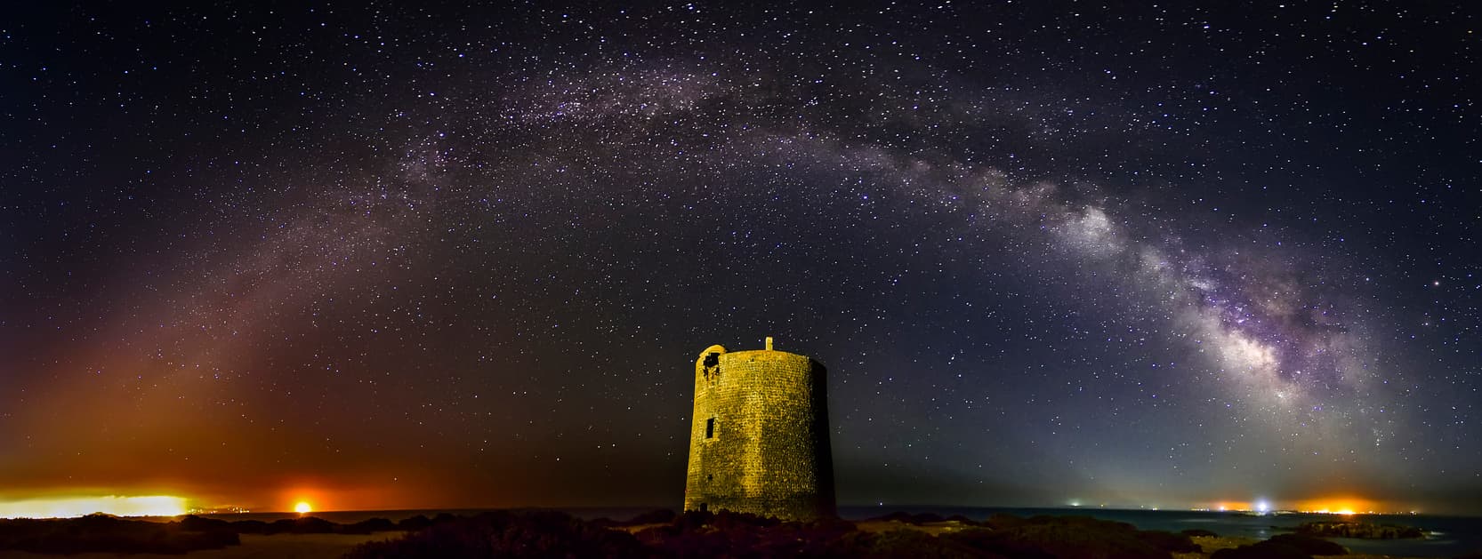 Une tour ancienne devant un panorama de la Voie Lactée