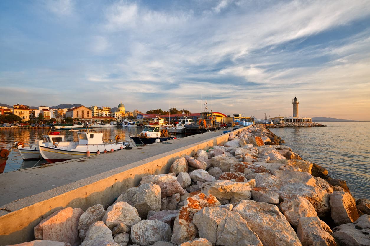 Dock path surrounded by stones and small boats to the lighthouse in Patra, Greece.