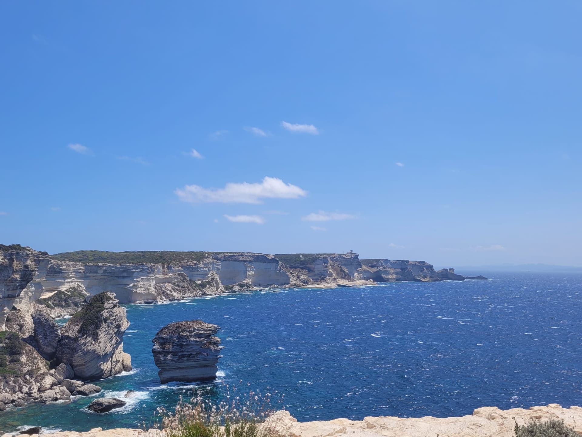 Une falaise impressionnante devant une mer agitée.