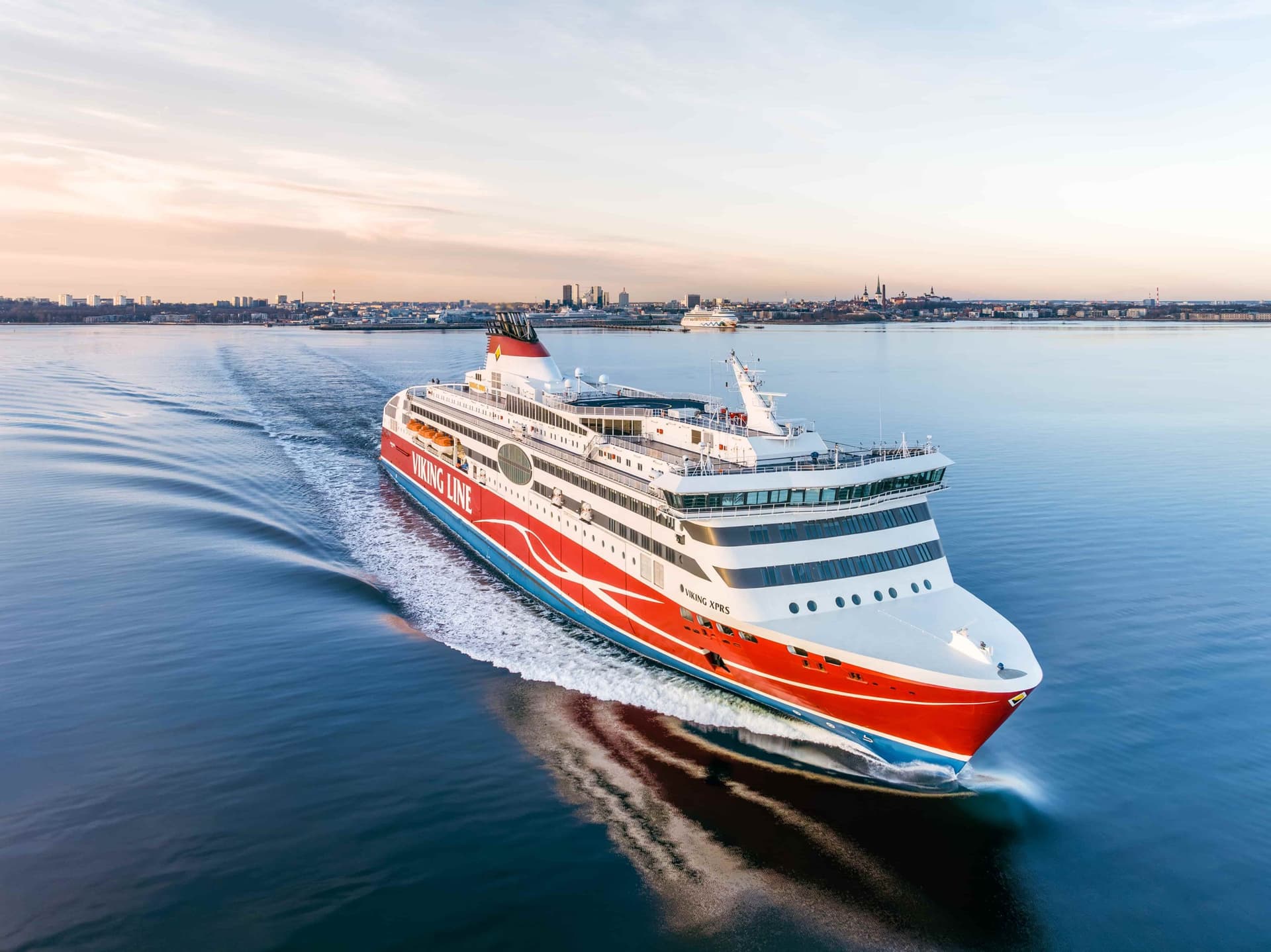 A large red-and-white ship sailing into the sunset off the coast of Tallinn