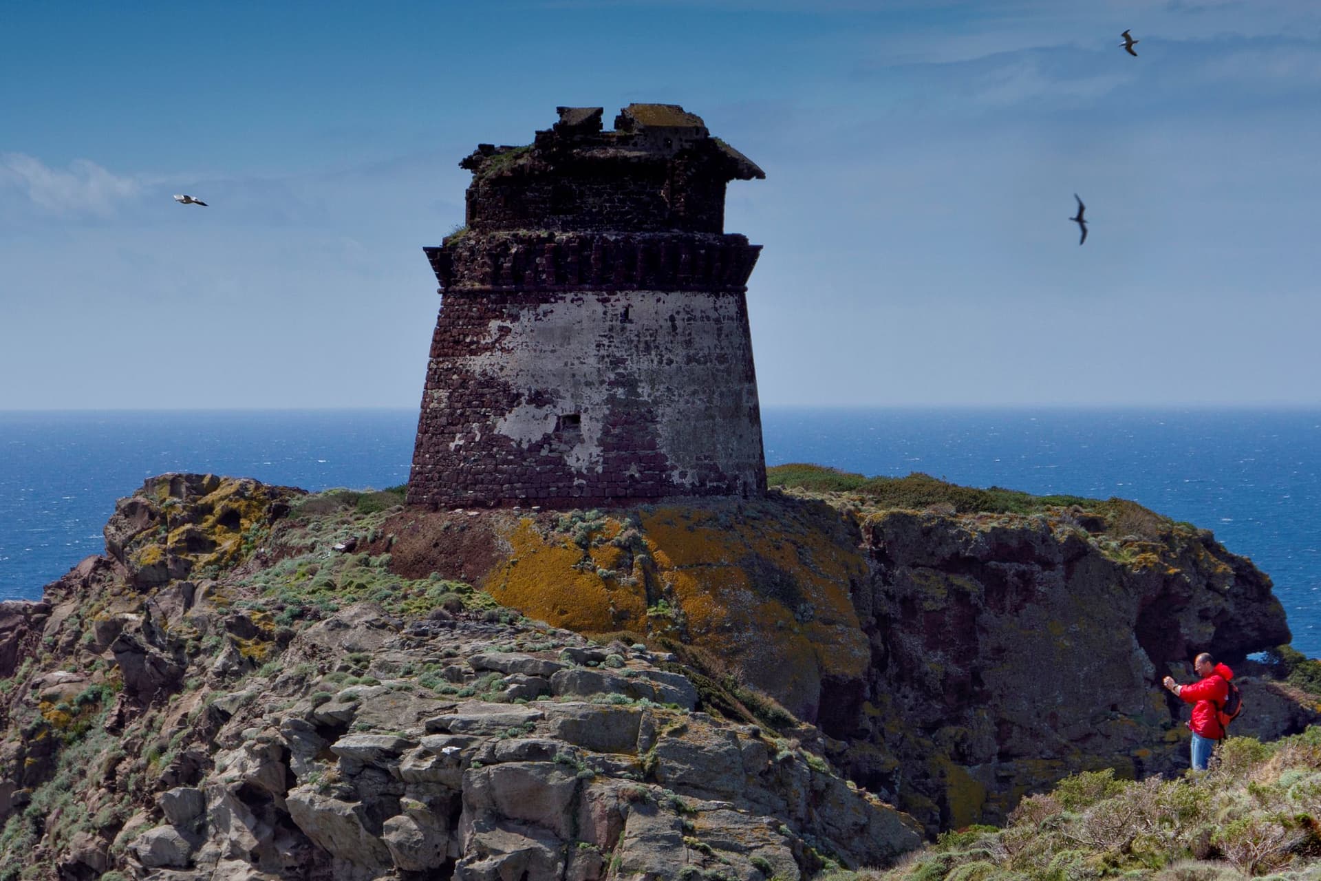 An old lighthouse rests on a cliff in Capraia, Italy.