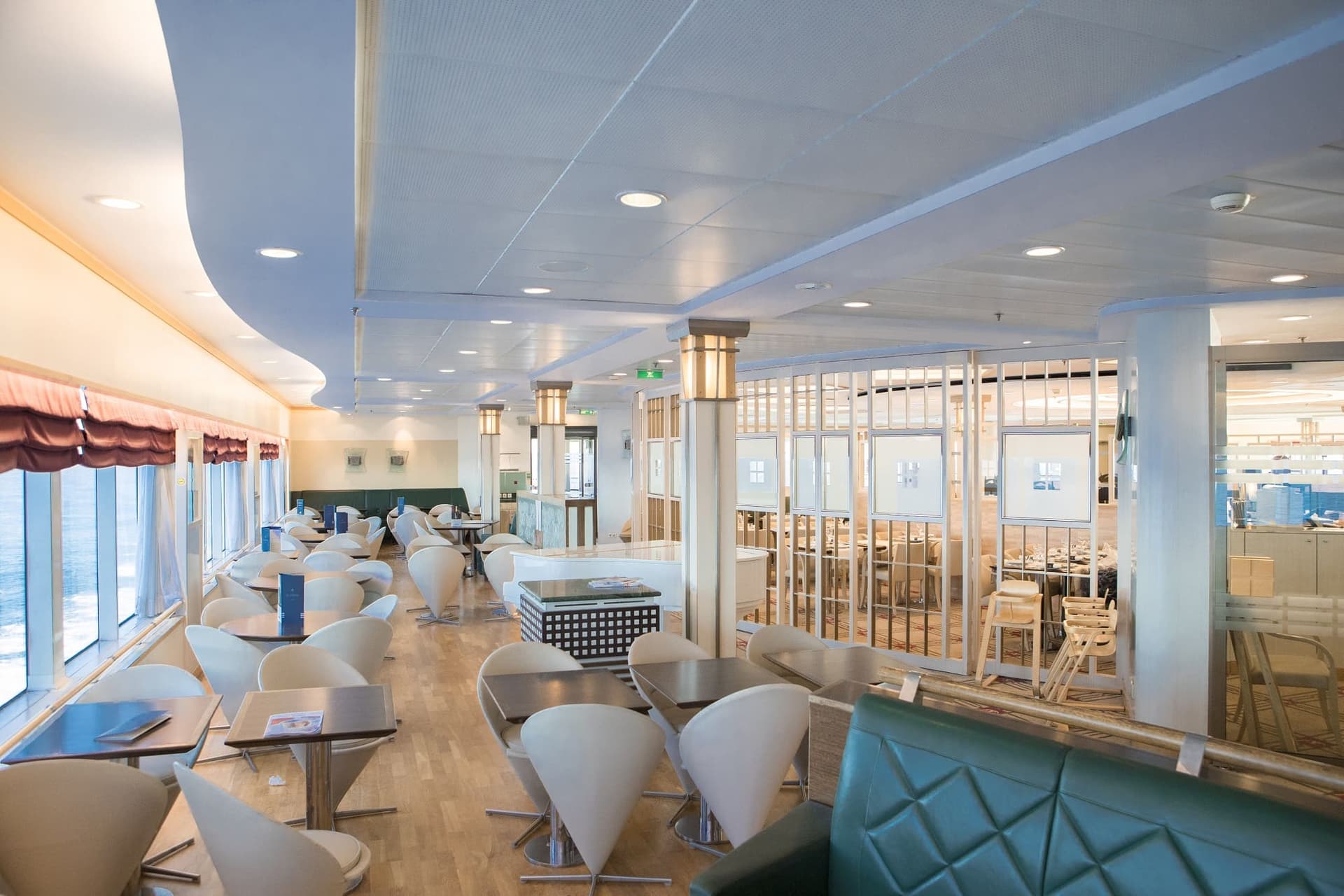 Lounge area with cream coloured chairs, wooden tables and flooring on the Pont-Aven ferry.
