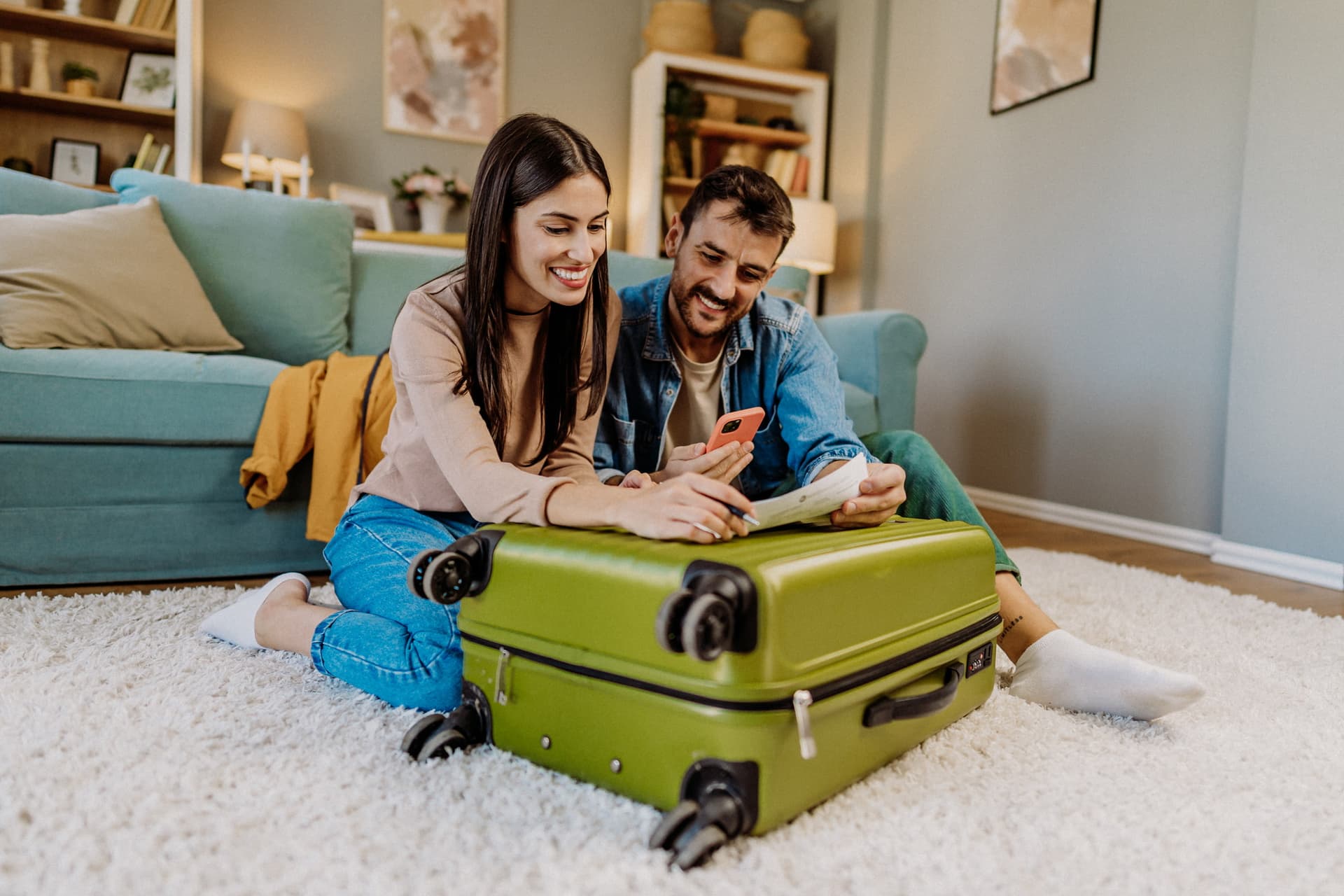 Un couple prêt à partir en vacances, les valises prêtes et un téléphone à la main.
