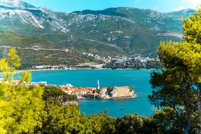Panorama di Budva in Montenegro con centro storico sul mare, acqua turchese e montagne sullo sfondo.