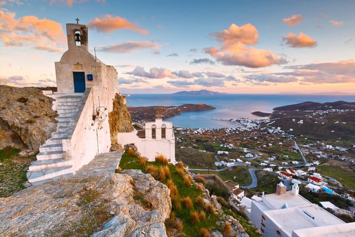 Chiesa tradizionale sulla collina di Chora a Serifos con vista panoramica sul porto, sul Mar Egeo e sui villaggi dell'isola al tramonto.