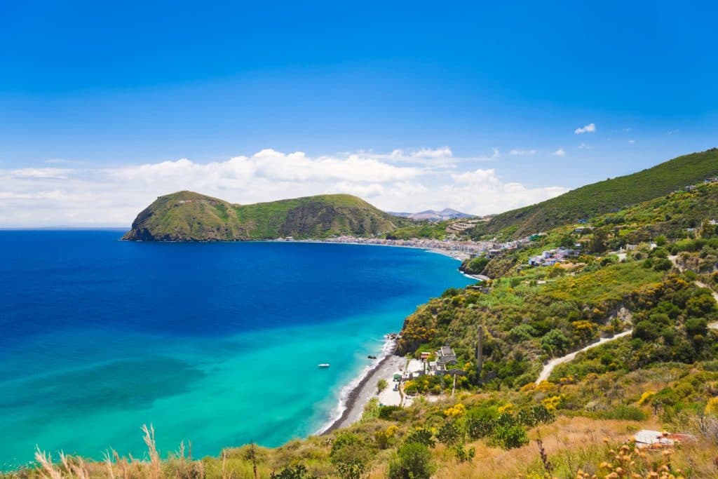 Panorama di Lipari nelle Isole Eolie con acque cristalline, spiaggia e paesaggio collinare affacciato sul Mar Tirreno.