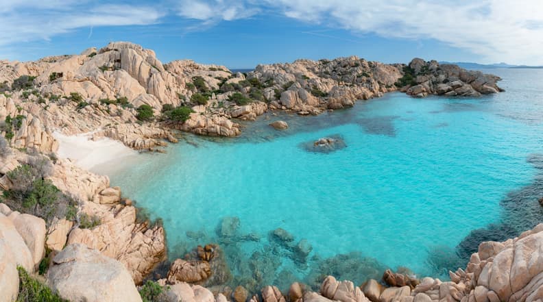 Cala Coticcio a Caprera, spiaggia di sabbia bianca circondata da rocce di granito rosa e mare turchese cristallino.