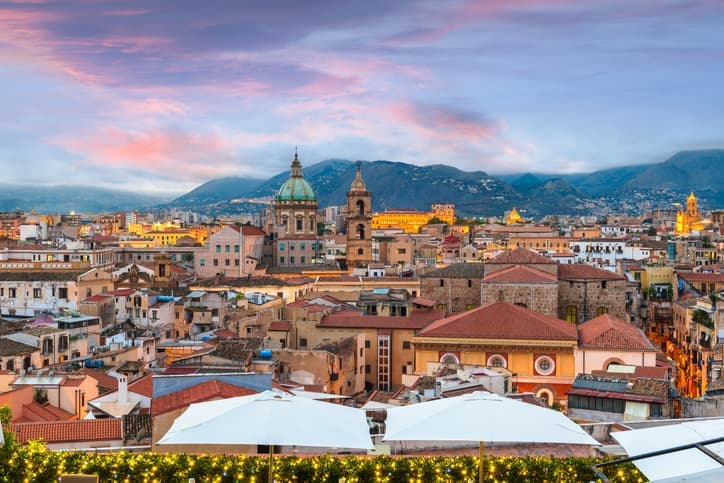 Vista panoramica di Palermo al tramonto con cupole della cattedrale e tetti del centro storico
