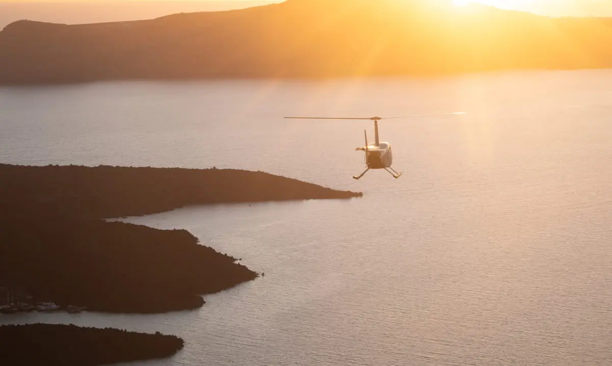 Helicopter flying over the sea at sunset, offering an alternative travel option between destinations.